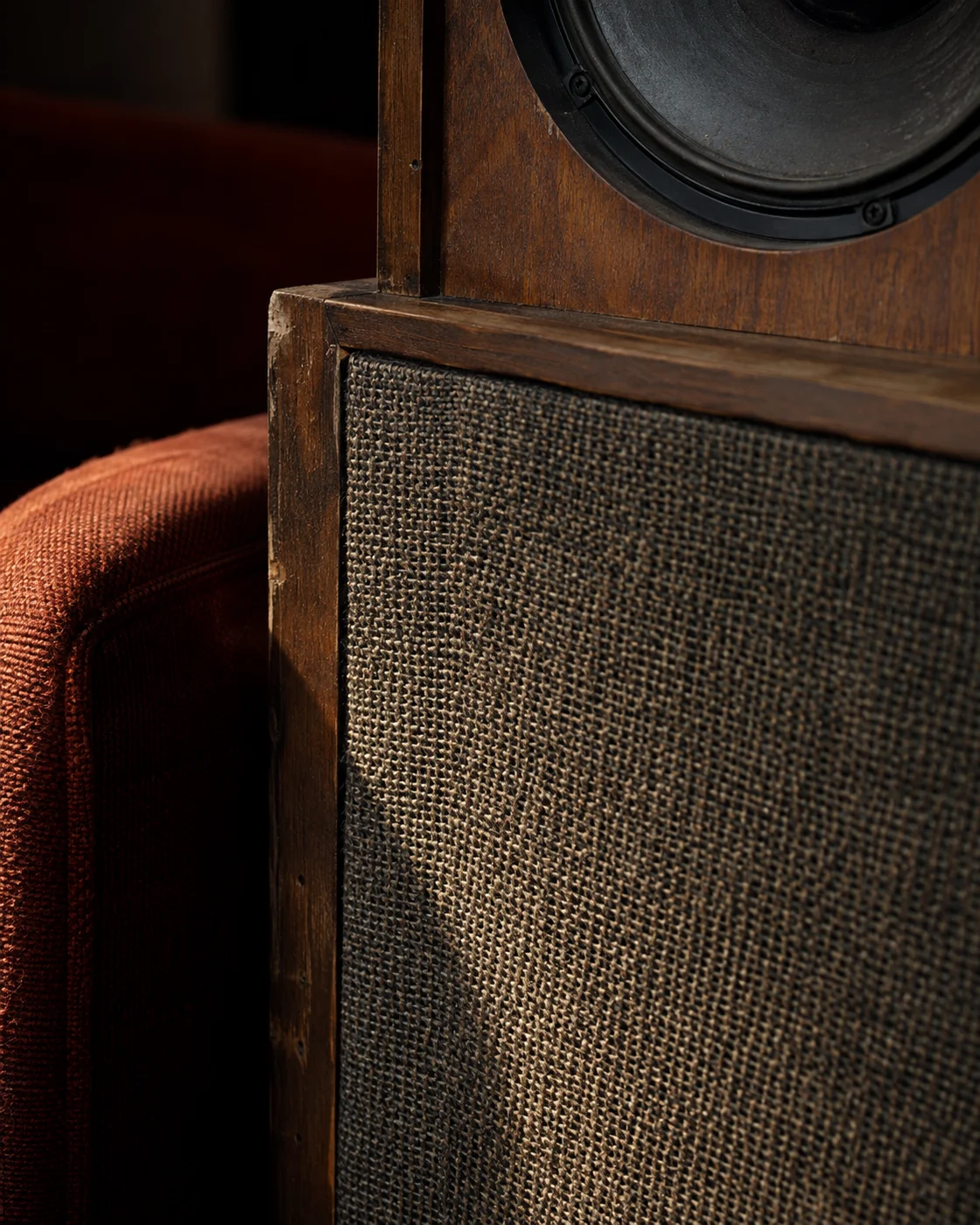 Close-up of woven speaker cloth and the worn walnut edge of a vintage loudspeaker